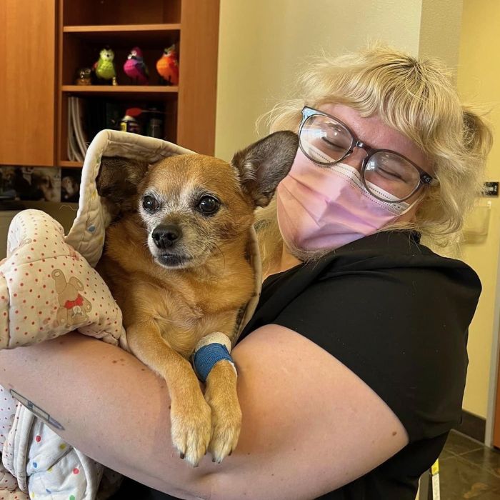 A masked woman cradles her dog